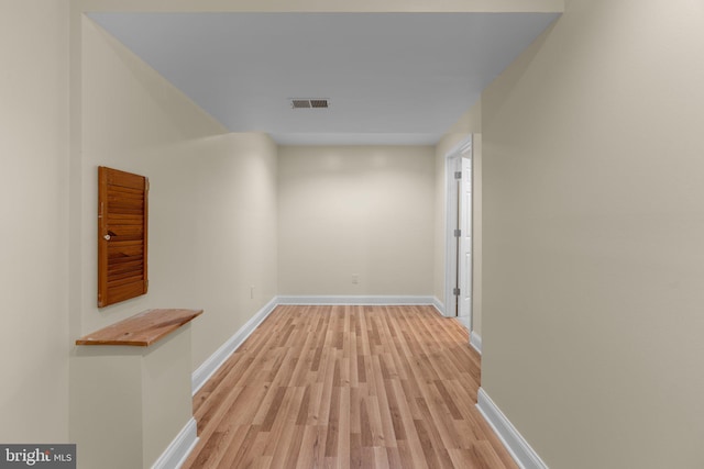 corridor with light wood-style flooring, baseboards, and visible vents