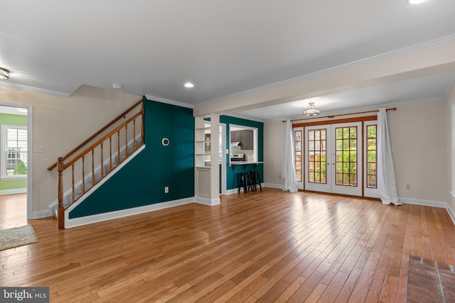 unfurnished living room featuring baseboards, a wealth of natural light, ornamental molding, and light wood-style floors