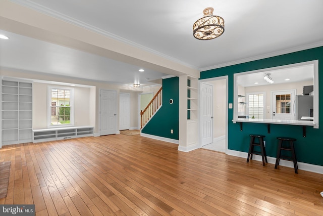foyer entrance featuring crown molding, light wood-style floors, stairway, and baseboards