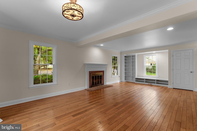 unfurnished living room featuring a brick fireplace, crown molding, baseboards, light wood-style floors, and recessed lighting
