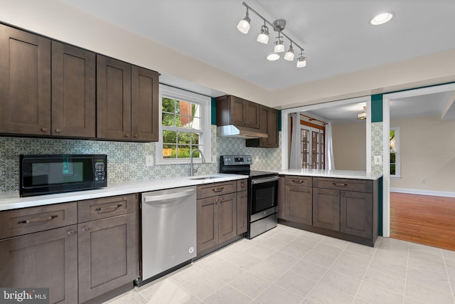 kitchen with stainless steel appliances, under cabinet range hood, dark brown cabinets, a sink, and light countertops