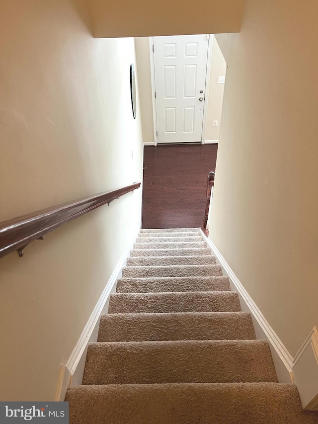 staircase with baseboards and wood finished floors