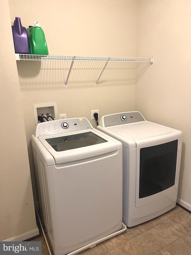 clothes washing area featuring laundry area, baseboards, and washing machine and dryer