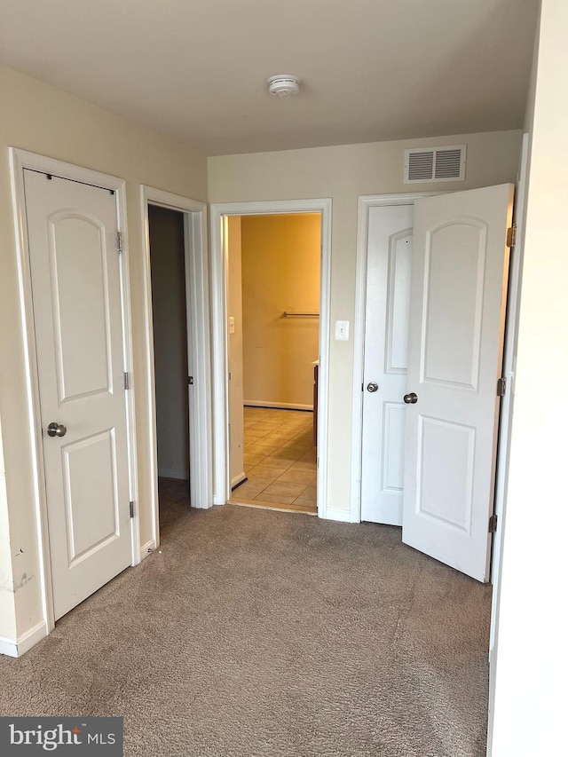 unfurnished bedroom with baseboards, visible vents, ensuite bathroom, and carpet