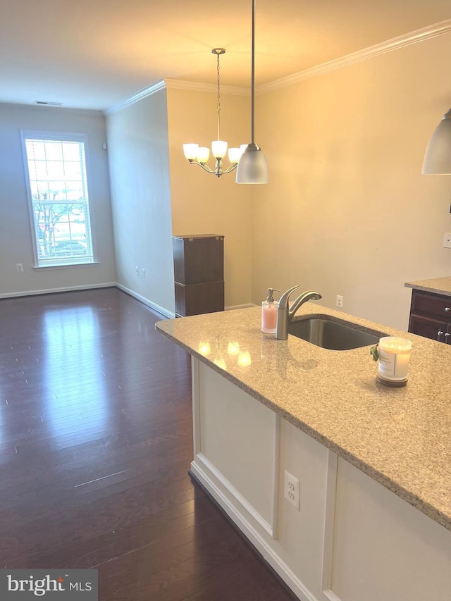 kitchen with crown molding, a sink, light stone counters, dark wood-style floors, and a notable chandelier