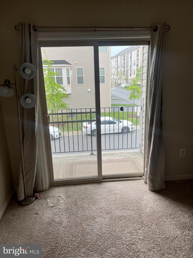 doorway to outside featuring baseboards and carpet