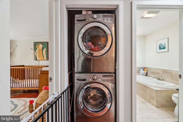 washroom featuring tile patterned flooring, laundry area, and stacked washer and dryer