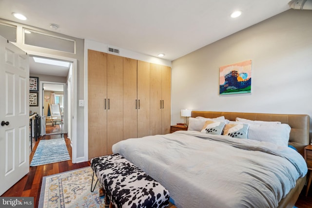 bedroom with a closet, recessed lighting, dark wood-style flooring, and visible vents