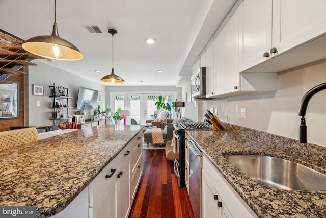 kitchen with a sink, dark wood-style floors, open floor plan, stainless steel appliances, and white cabinetry