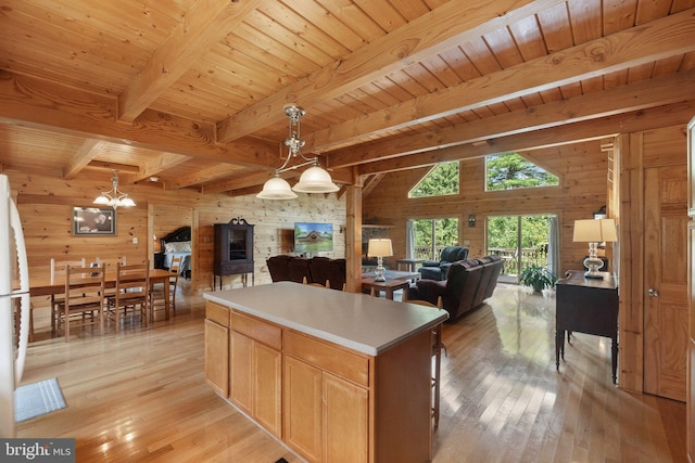 kitchen with wood walls, beamed ceiling, a notable chandelier, light wood-style flooring, and open floor plan
