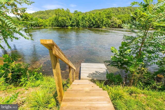 view of dock featuring a water view and a forest view