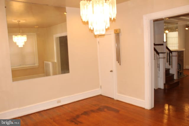 unfurnished dining area with stairway, baseboards, wood finished floors, and a chandelier