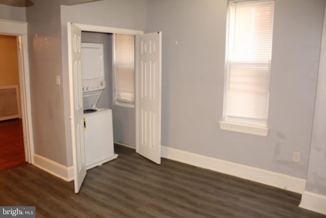 laundry room featuring baseboards, laundry area, dark wood-style floors, and stacked washer / dryer