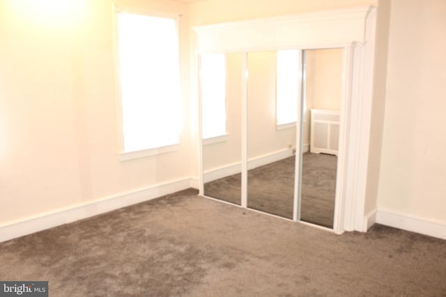 unfurnished bedroom featuring baseboards, carpet, and radiator heating unit