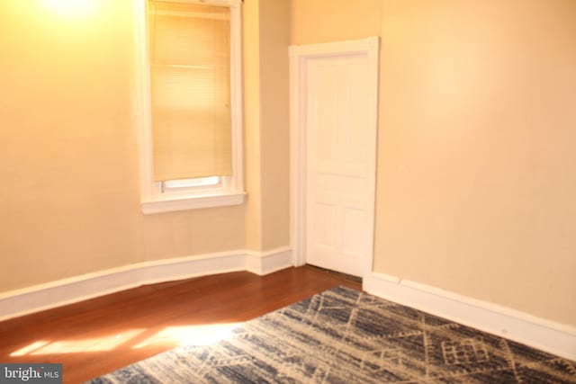 empty room with baseboards and dark wood finished floors