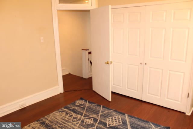 unfurnished bedroom with a closet and dark wood finished floors