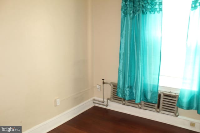 spare room featuring baseboards and dark wood-style floors