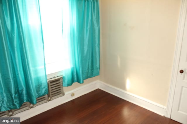 empty room with baseboards and dark wood-type flooring