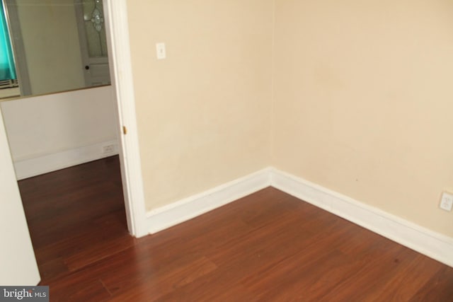 empty room with baseboards and dark wood-style floors