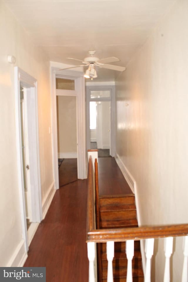 hall featuring baseboards, dark wood finished floors, and stairs