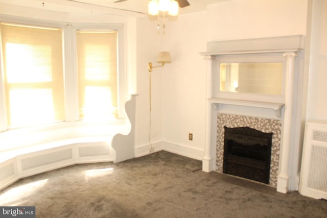 unfurnished living room featuring carpet flooring, ceiling fan, radiator heating unit, and a fireplace