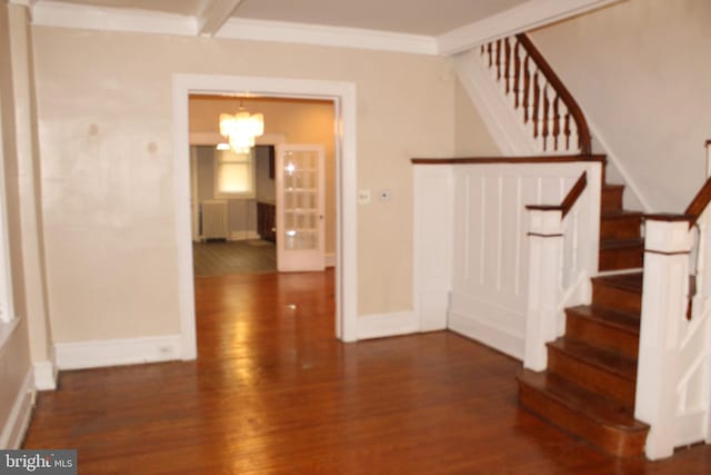 stairway with a chandelier, radiator heating unit, baseboards, wood finished floors, and ornamental molding