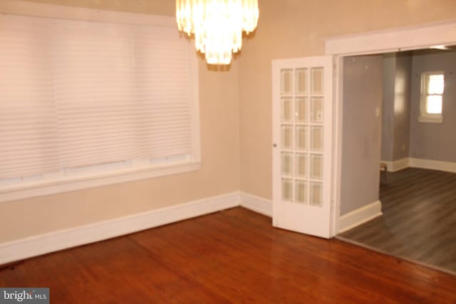 unfurnished dining area with baseboards, a chandelier, and wood finished floors