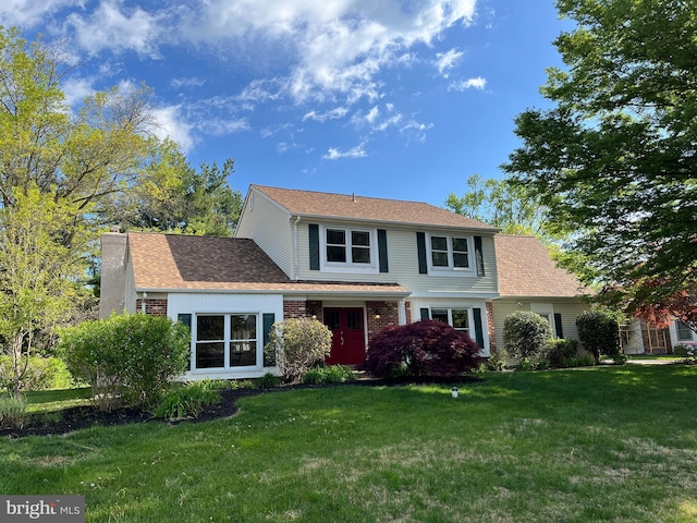 traditional home with a chimney, a shingled roof, and a front yard