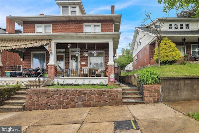 american foursquare style home featuring a porch and brick siding