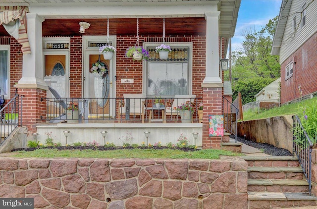 property entrance with covered porch and brick siding