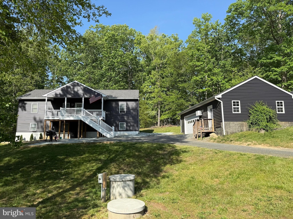 view of front facade featuring a front yard, a wooden deck, a garage, stairway, and an outdoor structure