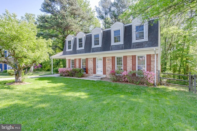 view of front of property featuring brick siding, fence, a shingled roof, and a front yard
