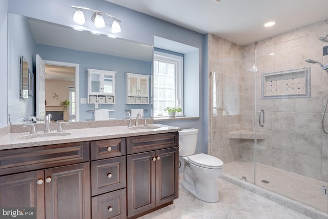 full bath with a sink, a stall shower, toilet, and double vanity