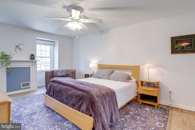 bedroom featuring visible vents, a ceiling fan, baseboards, and wood finished floors