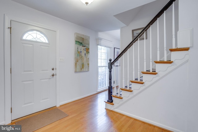 entryway featuring stairs, baseboards, plenty of natural light, and light wood-type flooring