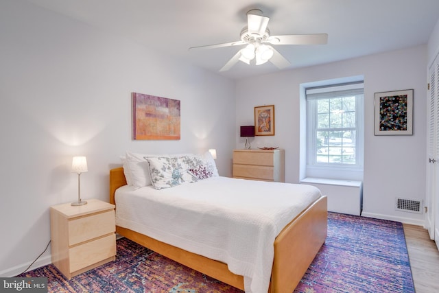 bedroom featuring visible vents, baseboards, ceiling fan, and wood finished floors