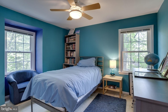 bedroom with baseboards, a ceiling fan, light carpet, and multiple windows
