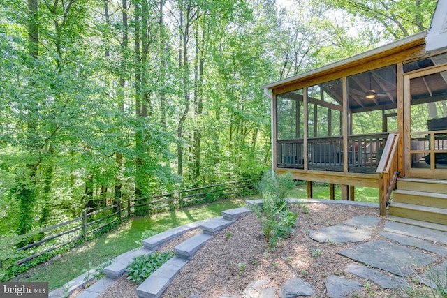 view of yard with a fenced backyard, a wooden deck, and a sunroom