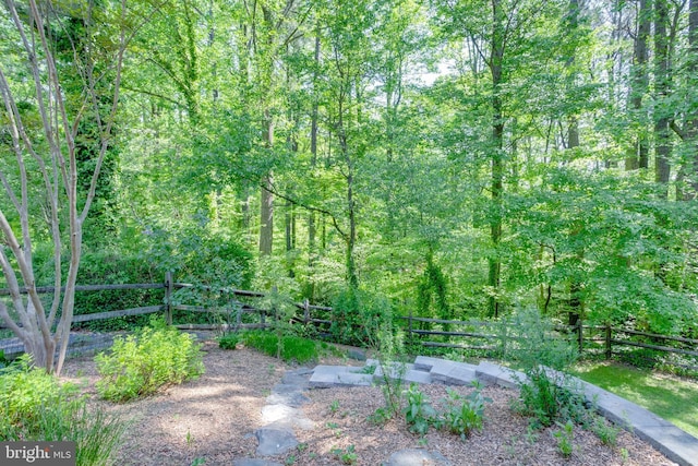view of yard with fence and a wooded view