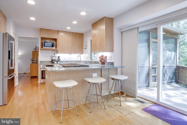kitchen with visible vents, a peninsula, a wealth of natural light, and stainless steel appliances
