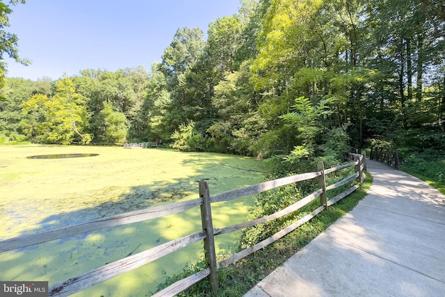 exterior space with a lawn, a forest view, and fence