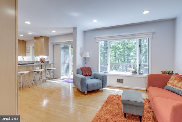 living room featuring recessed lighting, baseboards, visible vents, and light wood-style flooring