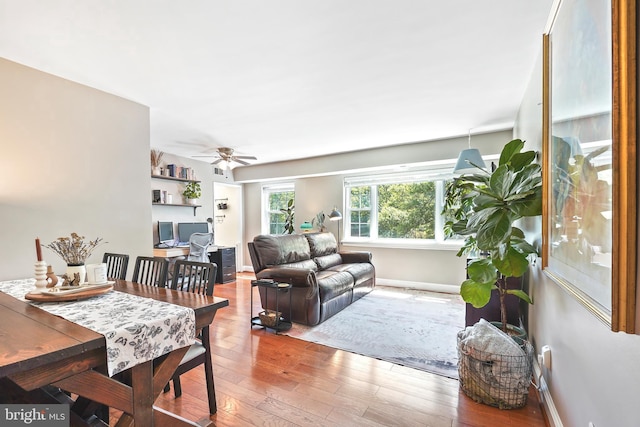 living area with a ceiling fan, baseboards, and hardwood / wood-style floors