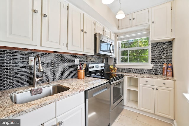 kitchen with a sink, appliances with stainless steel finishes, light tile patterned flooring, and white cabinets