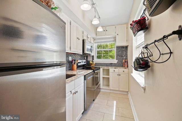 kitchen with white cabinetry, backsplash, light tile patterned floors, and stainless steel appliances