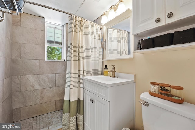 full bathroom featuring vanity, toilet, and tiled shower