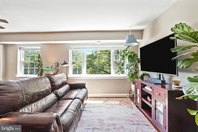living area with baseboards and ceiling fan