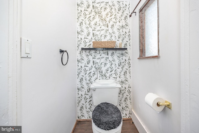 bathroom featuring baseboards, wood finished floors, and toilet