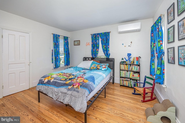 bedroom featuring wood finished floors and a wall mounted air conditioner
