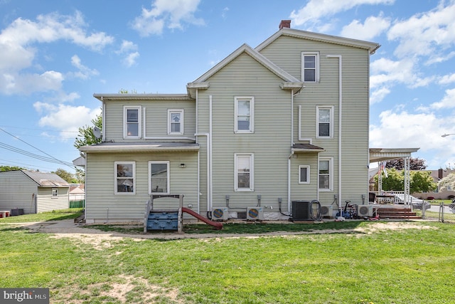 back of property with a lawn, ac unit, central air condition unit, and a chimney